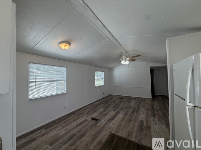 A spacious room with wood flooring and a ceiling fan.