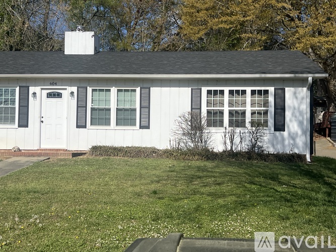 A white house with a black roof and a chimney.
