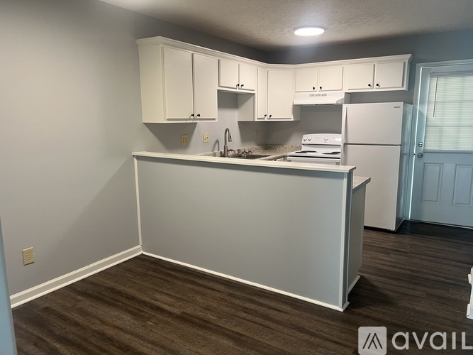A kitchen with white cabinets and a wooden floor.