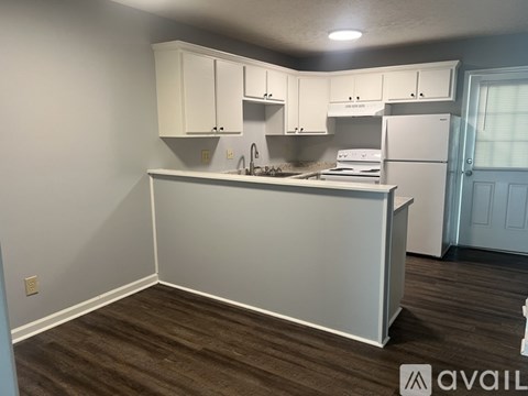A kitchen with white cabinets and a wooden floor.