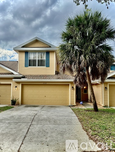 A house with a tan roof and a palm tree in front.