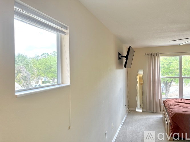 A bedroom with a window and a bed in the background.