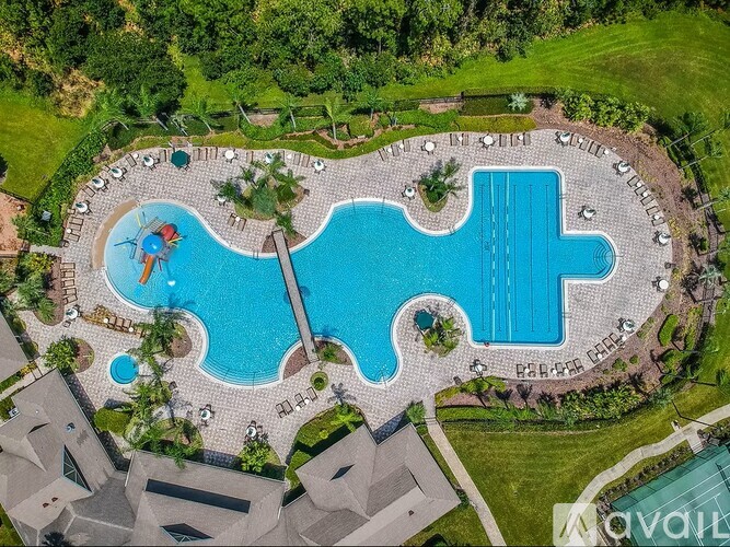 A large outdoor swimming pool surrounded by a stone patio and a grassy area.