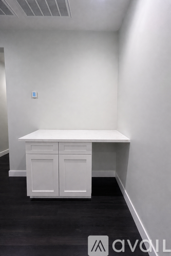 A white desk with two drawers and a cabinet in a room.