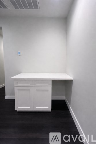 A white desk with two drawers and a cabinet in a room.