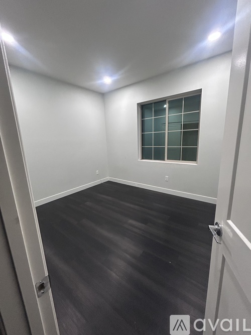 A room with a window and a wooden floor.