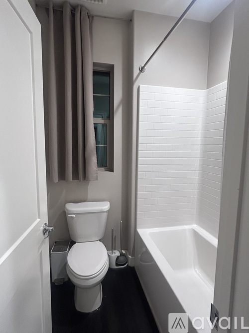A white toilet sits in a bathroom next to a white bathtub.