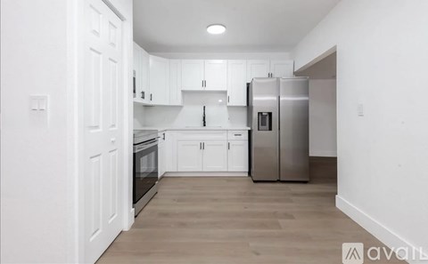 A kitchen with white cabinets and a wooden floor.