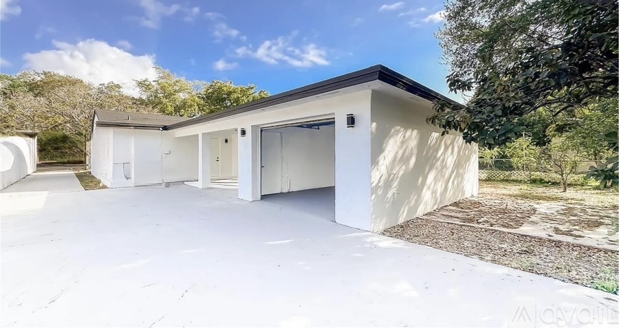 A modern house with a white exterior and a large driveway.