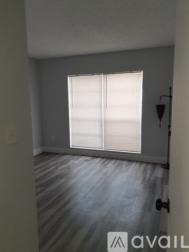 A room with a window covered by blinds and a wooden floor.