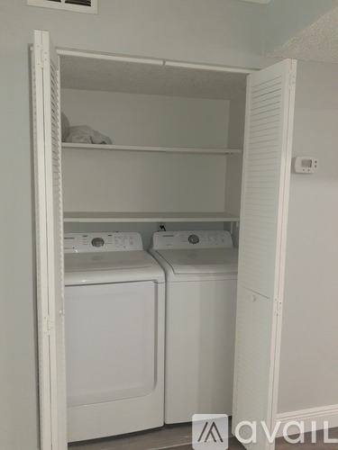 A white laundry room with two washing machines and a shelf.