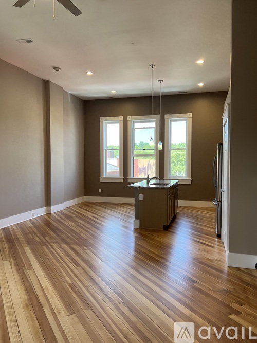 A spacious room with wooden flooring and a ceiling fan.