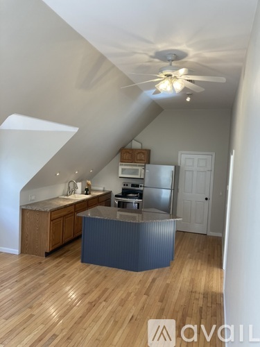 A kitchen with a wooden floor and a ceiling fan.