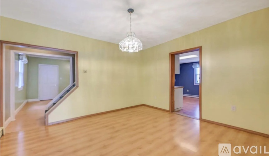 A room with wooden floors and a chandelier hanging from the ceiling.