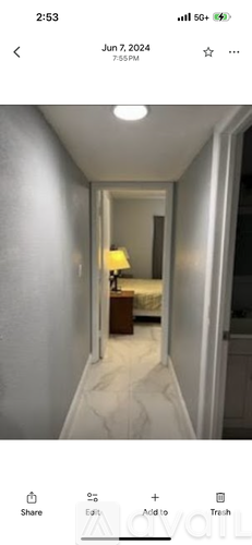 A narrow hallway with a lamp and a bedroom visible at the end.