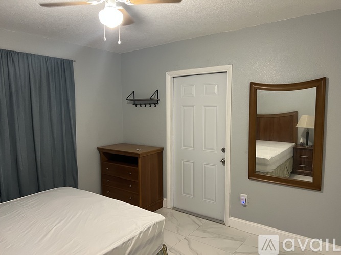 A bedroom with a bed, dresser, mirror, and a ceiling fan.