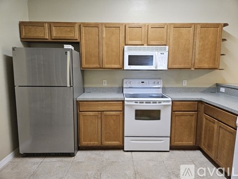 A kitchen with wooden cabinets and a stainless steel refrigerator.