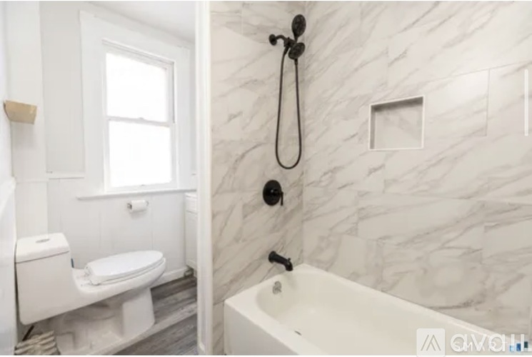 A white bathroom with a marble wall and a white bathtub.