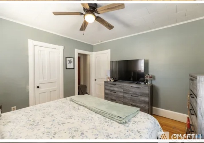 A bedroom with a bed, dresser, and ceiling fan.