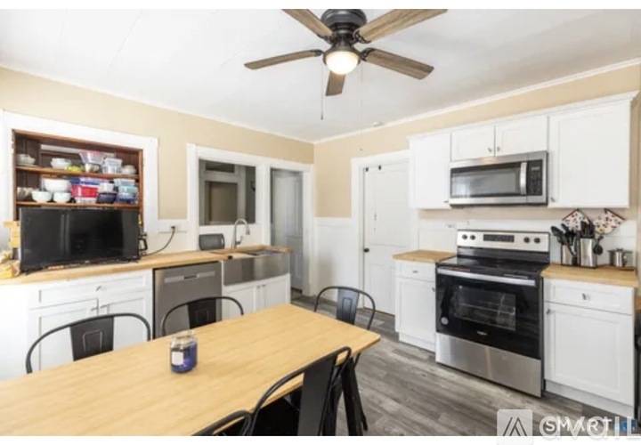 A kitchen with a table and chairs in the foreground and a microwave on top of the oven.
