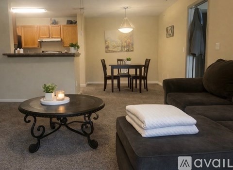 A living room with a black couch, a round table with candles, and a dining table with chairs.