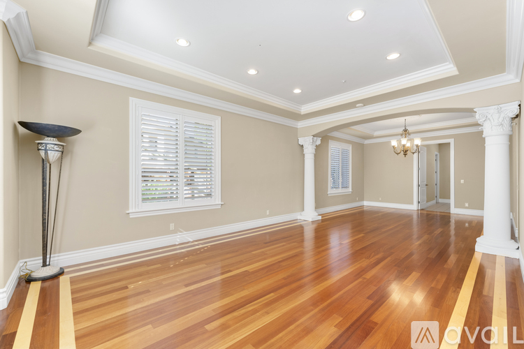 A spacious room with wooden floors and white columns.