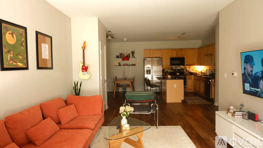 A living room with a red couch and a guitar on the wall.