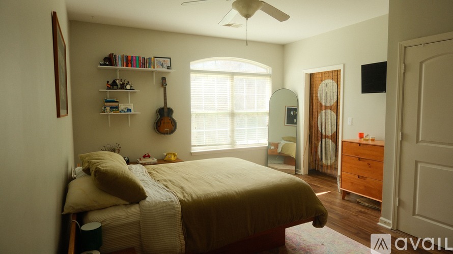 A bedroom with a bed, guitar, and shelves with various items.