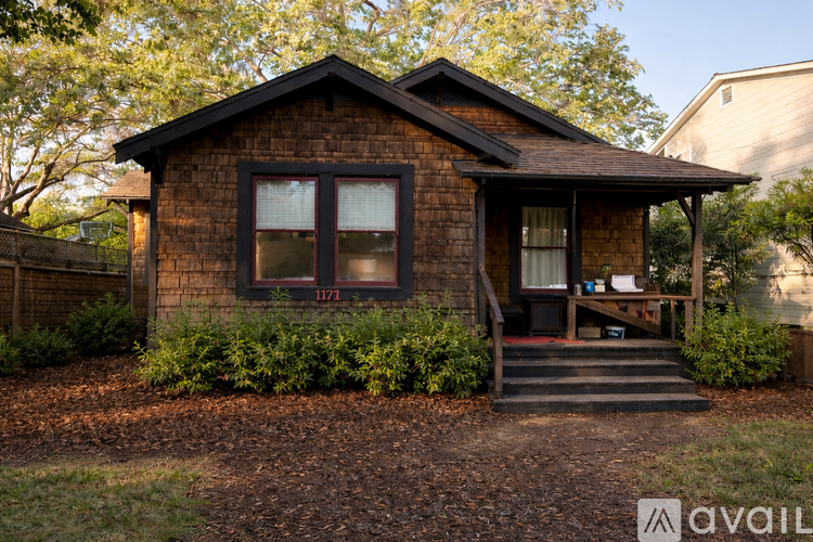A brown house with a porch and a small garden in front.