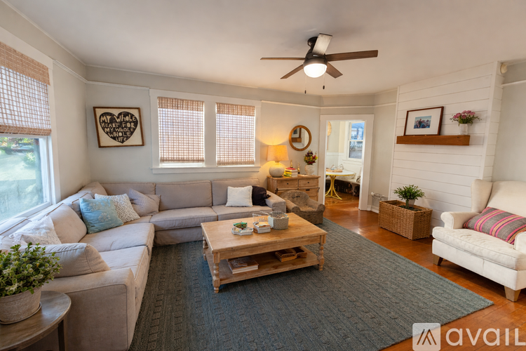 A living room with a white couch, a wooden coffee table, and a ceiling fan.