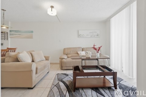A living room with a beige couch, a coffee table, and a painting on the wall.