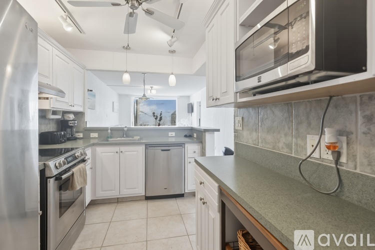 A kitchen with a stainless steel refrigerator and a microwave above the counter.
