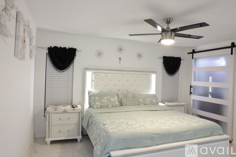 A bedroom with a bed, nightstand, and a ceiling fan.