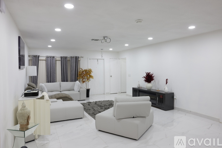 A modern living room with white furniture and a glass table.