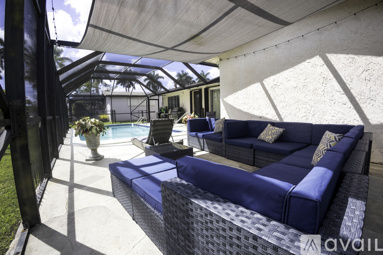 A blue couch is on a patio with a pool table and a glass roof.