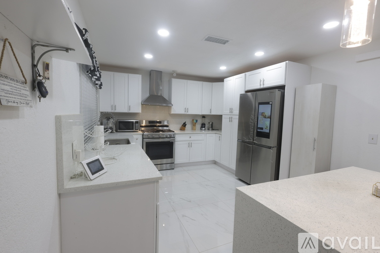 A kitchen with white cabinets and a white island.