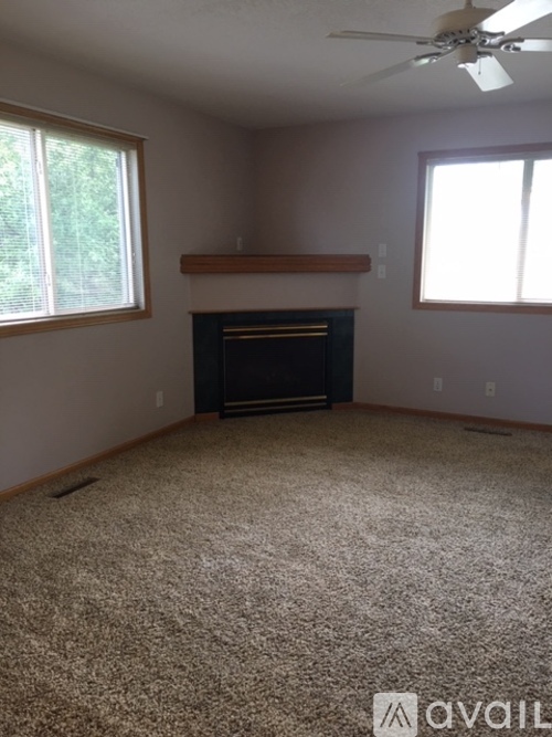 A living room with a fireplace and carpeted floor.