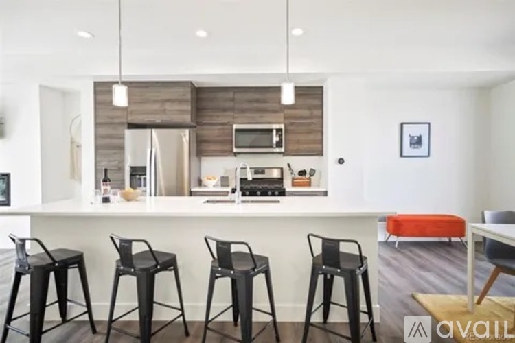 A modern kitchen with a bar area and four black chairs.
