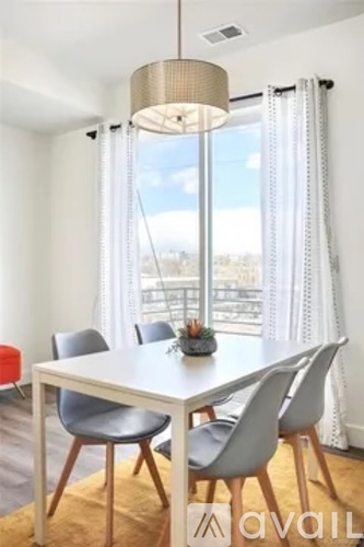 A dining room with a white table and grey chairs.