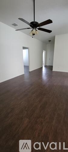 A room with a ceiling fan and wooden flooring.