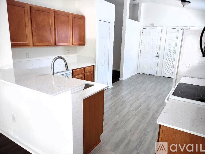 A kitchen with white countertops and wooden cabinets.