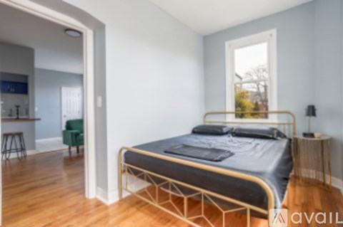 A bedroom with a bed, a chair, and a window.