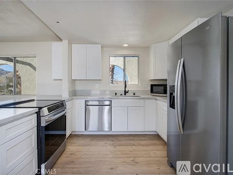 A kitchen with white cabinets and a stainless steel refrigerator.
