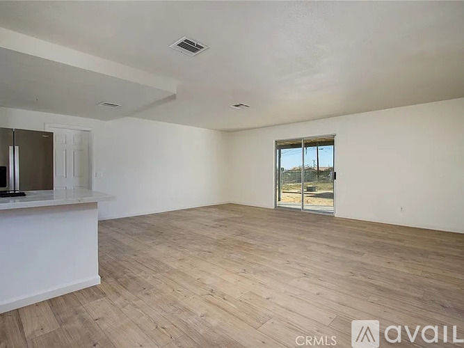 A spacious room with wooden flooring and a large window.