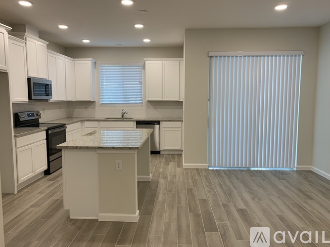 A kitchen with white cabinets and a marble island.