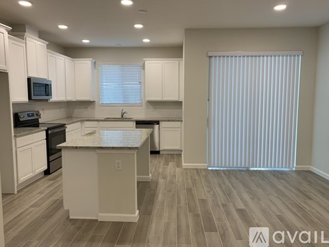 A kitchen with white cabinets and a marble island.