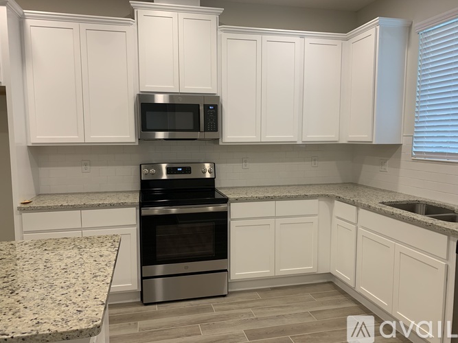 A kitchen with white cabinets and a granite countertop.