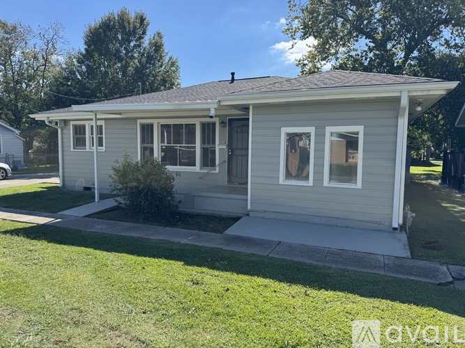A small house with a grey roof and white trim is for sale.