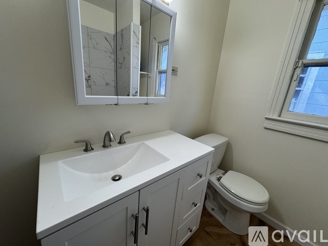 A bathroom with a white sink, toilet, and a mirror above the sink.