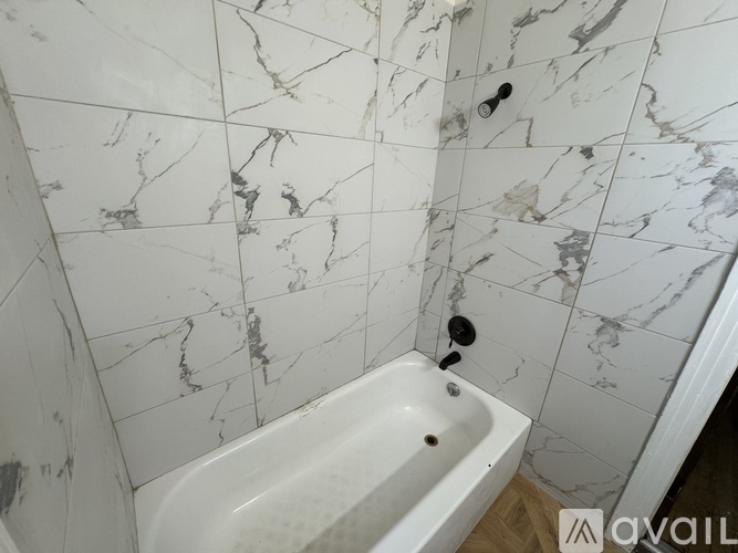 A white bathtub in a bathroom with marble tiles on the wall.